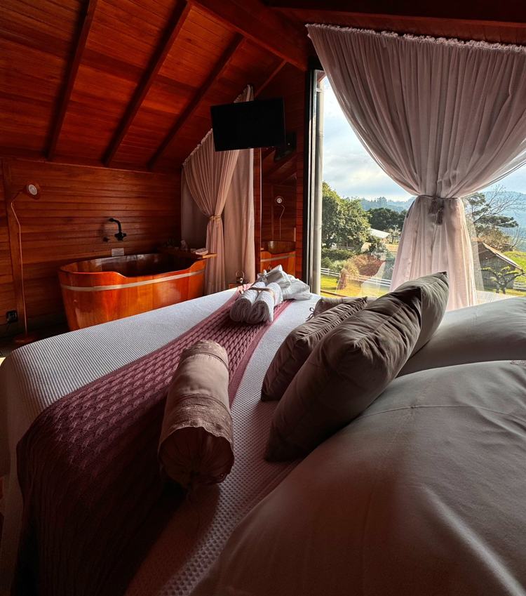 Cama da Cabana Rosé virada pra janela com vista das montanhas