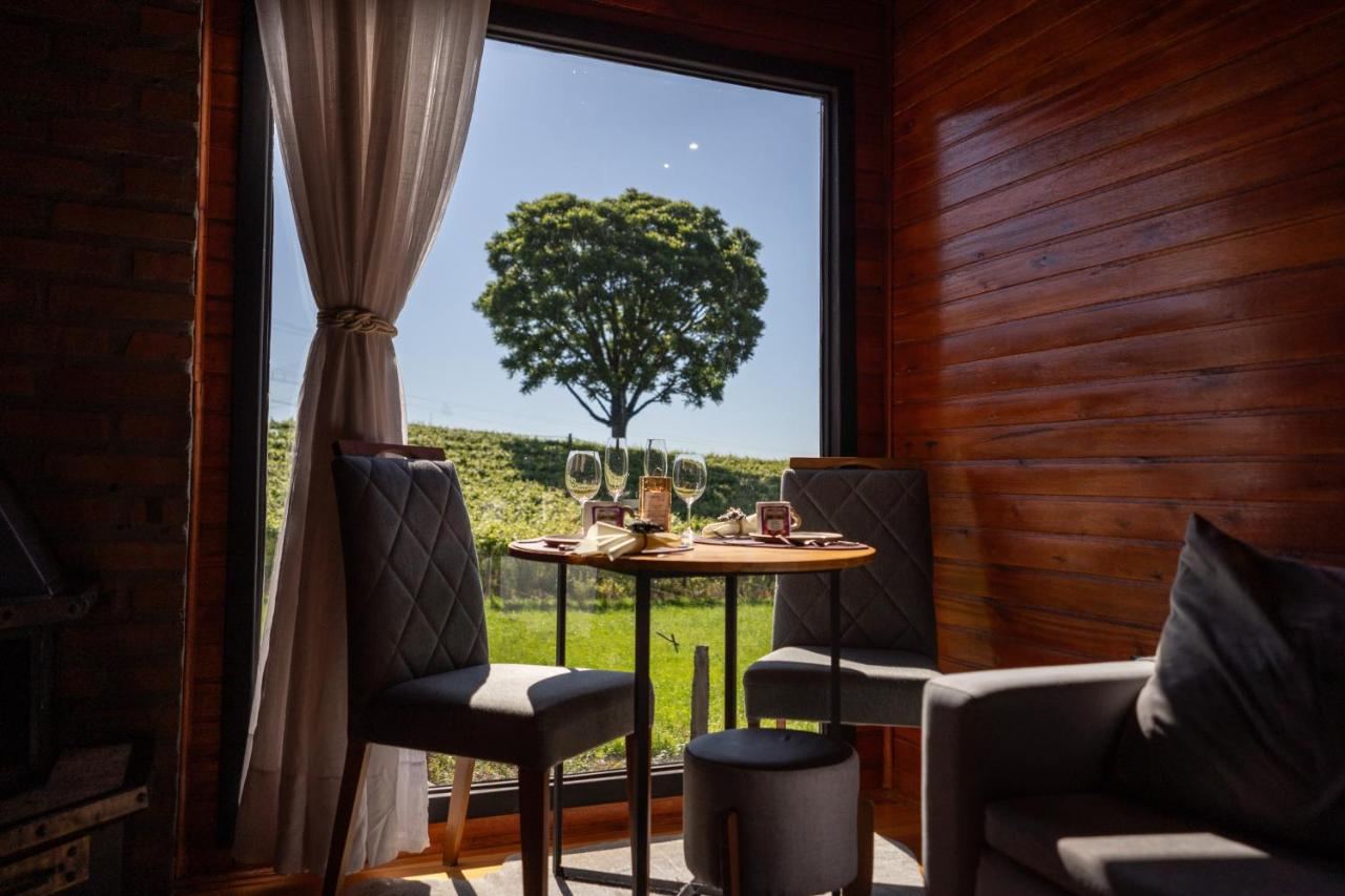 Mesa do café na cabana, de frente pra janela com a árvore